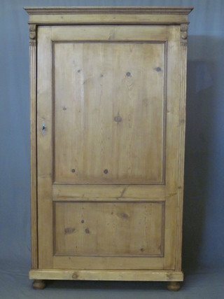 A Continental stripped and polished pine cupboard with moulded cornice, the shelved interior enclosed by panelled doors, raised  on bun supports 39"
