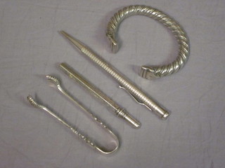 A heavy Eastern white metal bangle, a pair of silver sugar tongs,  a silver propelling pencil and an engraved silver plated dip pen