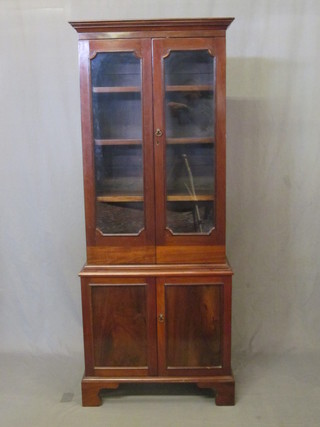 A Victorian mahogany bookcase on cabinet the upper section  with moulded cornice, the interior fitted adjustable shelves  enclosed by glazed panelled doors, the base fitted a cupboard  enclosed by glazed panelled doors, raised on bracket feet 26"