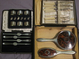 A silver plated and tortoiseshell effect 2 piece dressing table set with handmirror and clothes brush, a part set of silver plated fish  knives and forks, 4 silver plated lobster picks and 6 napkin ring  and place card holders, all cased