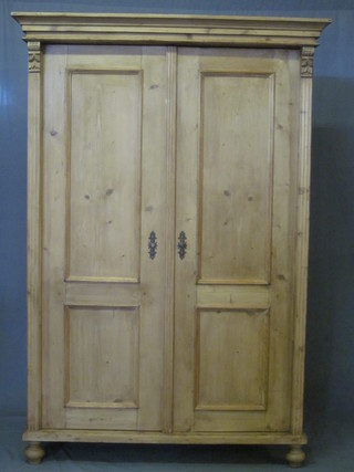 A Continental stripped and polished pine cupboard with moulded cornice, fitted shelves enclosed by panelled doors, raised on bun  feet 47"