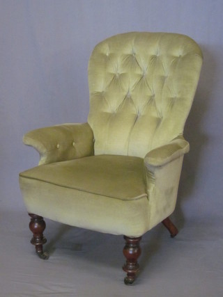 A Victorian mahogany framed armchair upholstered in green buttoned material, raised on turned supports ending in brass  castors