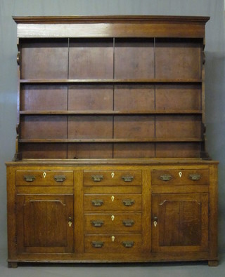 A Georgian oak dresser, the raised back with moulded cornice  and fitted 3 shelves, the base fitted 4 long drawers flanked by  cupboards with drawers above, raised on bracket feet, 66"   ILLUSTRATED
