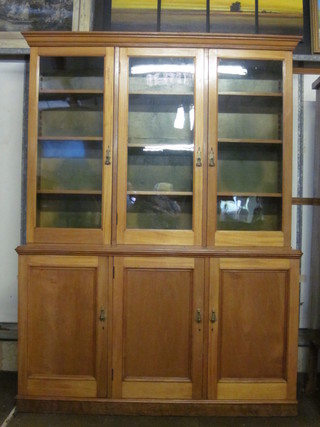 An Edwardian mahogany triple bookcase on cabinet, the upper section with moulded cornice, the shelved interior enclosed by glazed  panelled doors, the base fitted cupboards, raised on a platform  base 60"