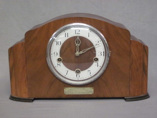 An Art Deco 8 day chiming mantel clock with silvered dial and Arabic numerals contained in an arch shaped walnut case
