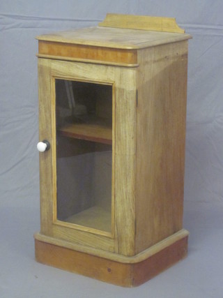 A Victorian bleached mahogany bedside cabinet with raised back,  the base enclosed by a glazed panelled door 16"