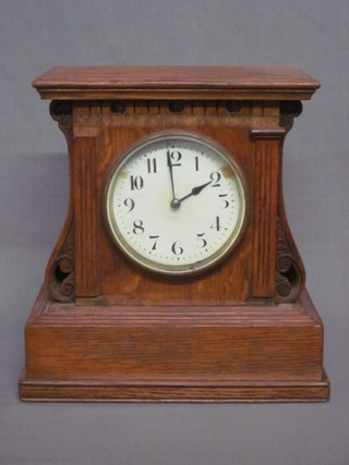 A Continental mantel clock with enamelled dial and Arabic numerals contained in a shaped oak case 7"