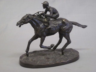 Mene, a bronze figure of a galloping race horse with jockey up,  raised on an oval naturalistic base 10"
