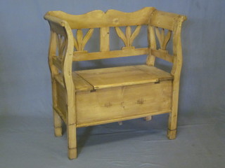 A Continental stripped and polished pine settle, the hinged seat revealing a storage compartment, 34"