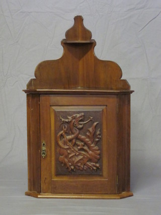 A Victorian carved walnut hanging corner cabinet, the interior fitted shelves enclosed by a panelled door carved a mythical beast  18"