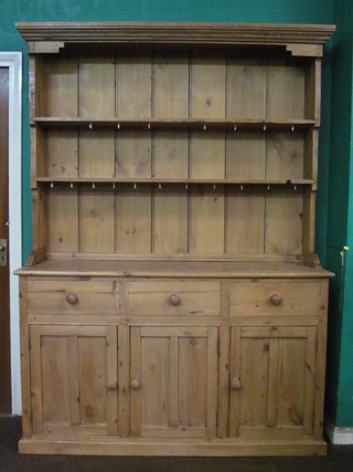 A stripped and polished pine dresser, the raised back with  moulded cornice and fitted 2 shelves, the base fitted 3 drawers  above a triple cupboard 59"