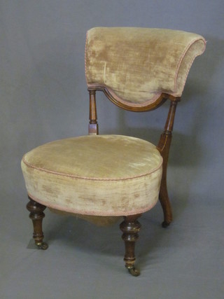 A Victorian walnut nursing chair upholstered in cream material