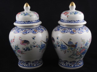 A pair of porcelain urns and covers decorated peacocks, the bases marked FG, 10"