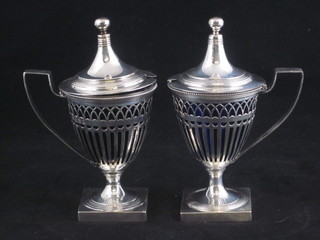 A handsome pair of Georgian style pierced silver mustard pots with hinged lids and blue glass liners, Birmingham 1911, 9 ozs   ILLUSTRATED
