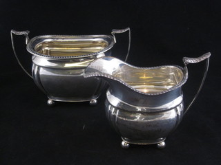 A Georgian style silver twin handled sugar bowl, raised on bun  feet together with a matching cream jug, Sheffield 1911, 9 ozs