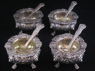 A handsome set of 4 William IV circular embossed silver salts with lion mask decoration, raised on paw feet, together with  matching spoons, London 1830, makers mark W E, 3 with clear  glass liners, 22 ozs  ILLUSTRATED