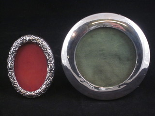 A circular silver easel photograph frame, Birmingham 1909 4"  and an oval embossed photograph frame, dents, 3"