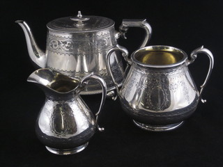 An oval engraved Britannia metal teapot, a silver plated twin handled sugar bowl and a matching cream jug