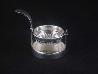 A modern silver plated tea strainer and stand