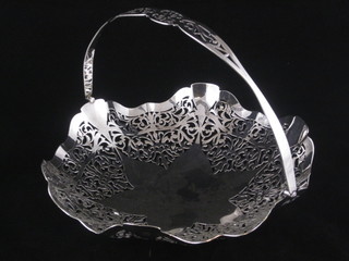 A circular pierced silver plated cake basket with swing handle,  raised on 3 bun feet