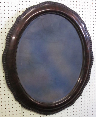 An oval bevelled plate wall mirror contained in a mahogany  finished frame 25"