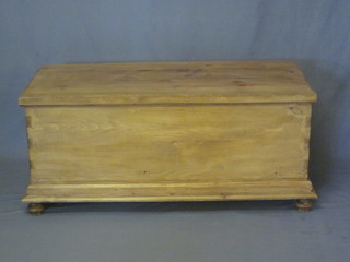 A stripped and polished pine coffer with hinged lid and iron drop handles, raised on bun feet 45"