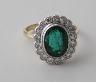 An 18ct yellow gold dress ring set an oval cut emerald  surrounded by diamonds, approx 0.5/2ct