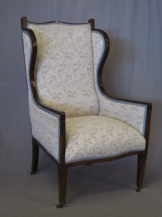 An Edwardian Art Nouveau mahogany show frame winged  armchair upholstered in blue material, raised on square tapering  supports