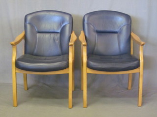 A pair of light oak showframe open arm chairs, the seats upholstered in blue leather
