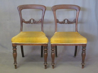 A pair of Victorian mahogany spoon back chairs with carved mid rails and upholstered seats, raised on turned supports