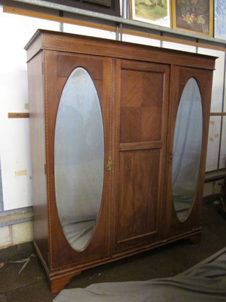 An Edwardian inlaid mahogany wardrobe with cornice and fitted interior enclosed by 2 arch panelled mirrored doors, raised on  bracket feet 58"