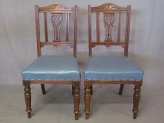 A set of 4 Edwardian carved walnut stick and rail back dining  chairs with upholstered seats, raised on turned supports