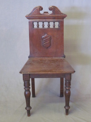 An Edwardian mahogany hall chair with solid seat and back,  raised on turned supports