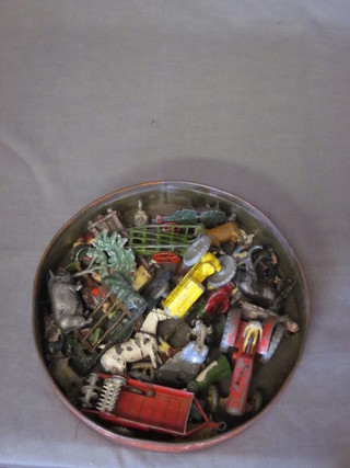 A circular metal biscuit tin containing a collection of Britain's metal farmyard figures etc