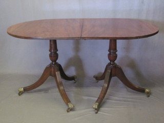 A Georgian style mahogany D end dining table with 1 extra leaf, raised on a pillar and tripod base