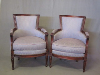 A pair of mahogany tub back armchairs upholstered in blue material, raised on turned and fluted supports