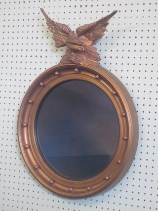 A convex plate wall mirror contained in a ball studded frame surmounted by a figure of an eagle, 16"