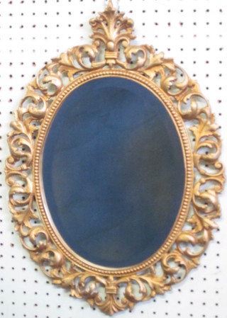 An oval bevelled plate mirror contained in a pierced gilt frame  19"