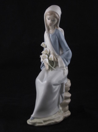 A Lladro figure of a seated lady with lilies, the base marked  D-26N 9", chip to head,