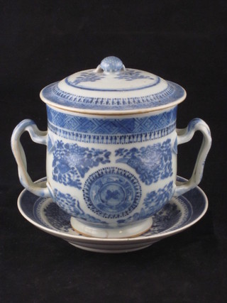 An Oriental blue and white porcelain twin handled cup and cover with strap work handles and matching saucer 5"