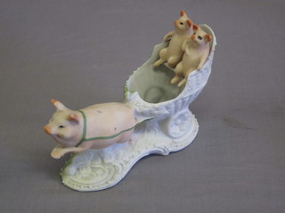 A biscuit porcelain figure in the form of 2 pigs in a carriage
