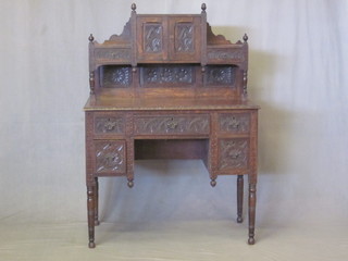 A Victorian carved oak writing table with raised back fitted a cupboard flanked by a pair of drawers, the base fitted 1 long and  2 short drawers 36"