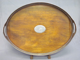 An oval wooden and silver plated twin handled galleried tea tray,  raised on bun feet 20"