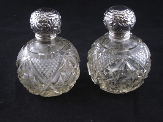 A pair of circular cut glass dressing table bottles with hinged silver lids, Birmingham 1913