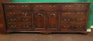 An 18th Century style elm dresser base fitted a drawer above a  double cupboard, flanked by 9 long drawers, raised on bracket  feet 90"