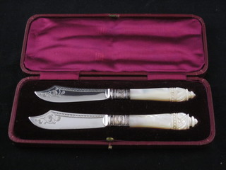 A pair of Victorian silver bladed butter knives with carved mother of pearl handles, cased