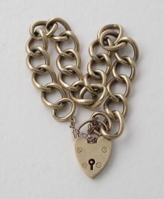 A gold curb link bracelet with heart shaped padlock clasp