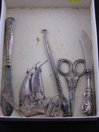 A pair of silver handled scissors, a silver model of an Eastern  Dowell, a button hook, 2 butter knives