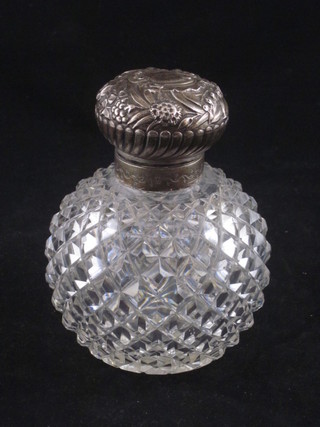A circular cut glass perfume bottle with embossed white metal lid 5"