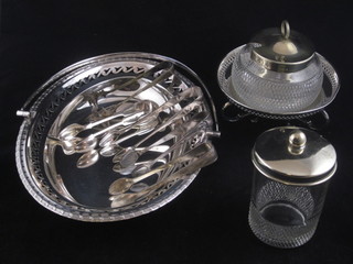 A cylindrical cut glass preserve jar with silver mount and 1 other,  a silver plated cake basket with swing handle and silver plated  sugar tongs